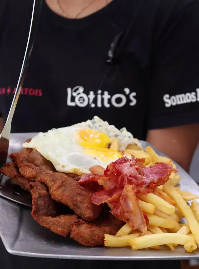 Integrante del equipo con remera de Lotito's sosteniendo un plato